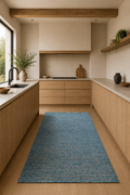 Modern kitchen with wooden cabinets, a blue rug on the floor, and natural light.