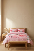 Bed with pink and white checkered bedding in a room with beige walls and wooden furniture.